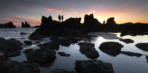 Two fishermen hop rocks at sunset on the Oregon Coast